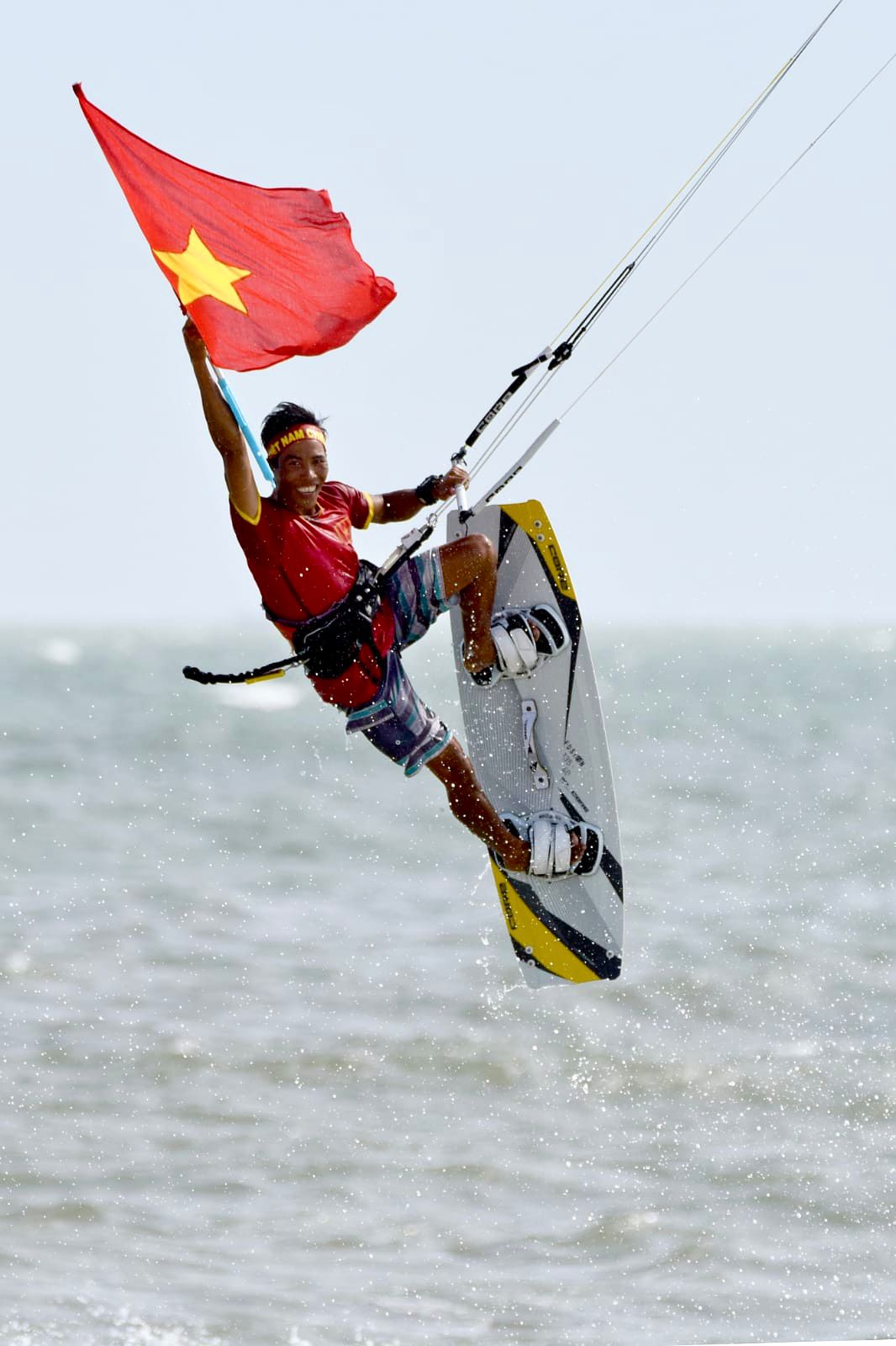 Lý jumping with the Vietnamese flag during a kitesurf competition in Mui Ne