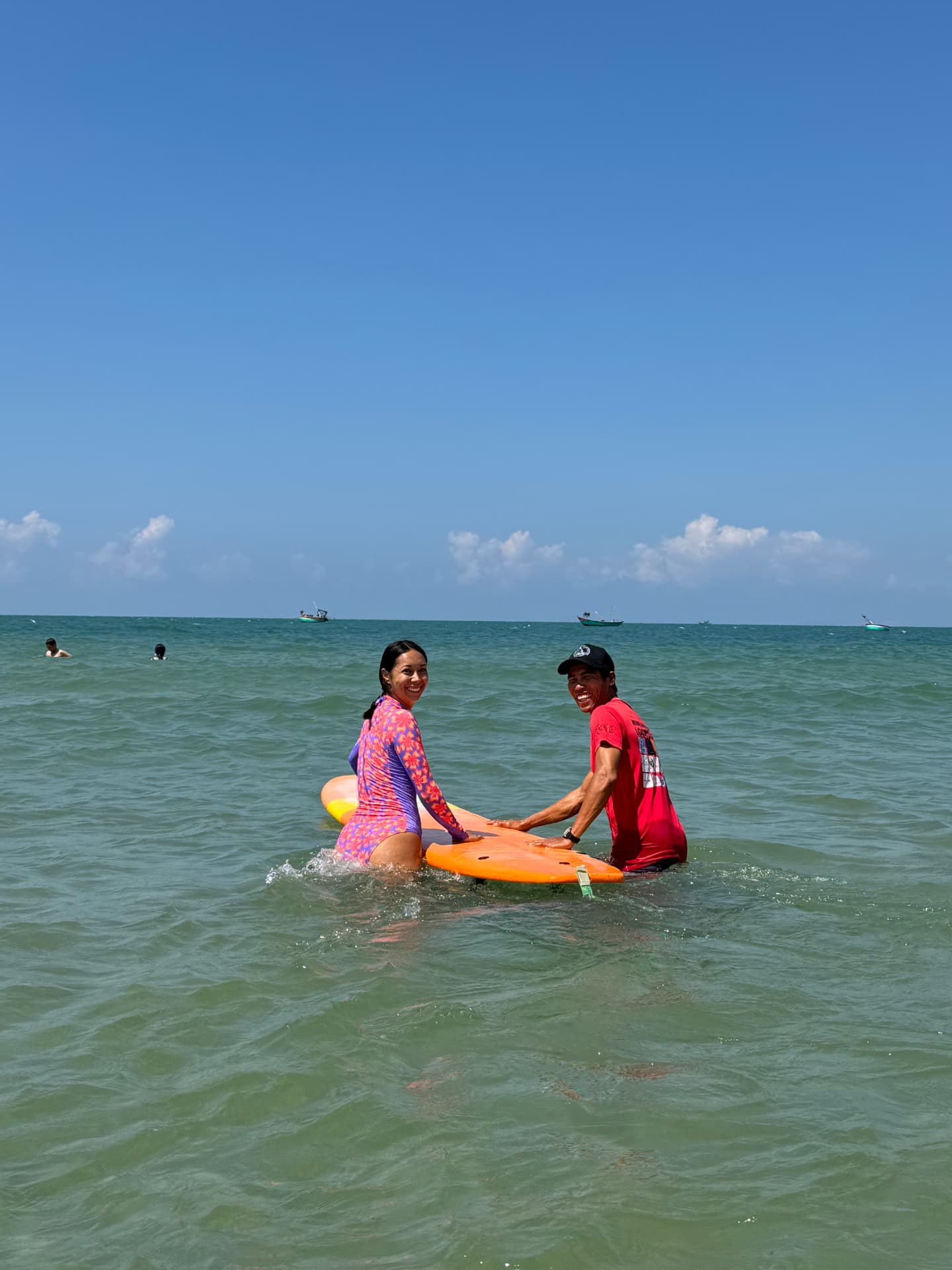 Surf student on a longboard in the water with Lý in Mui Ne