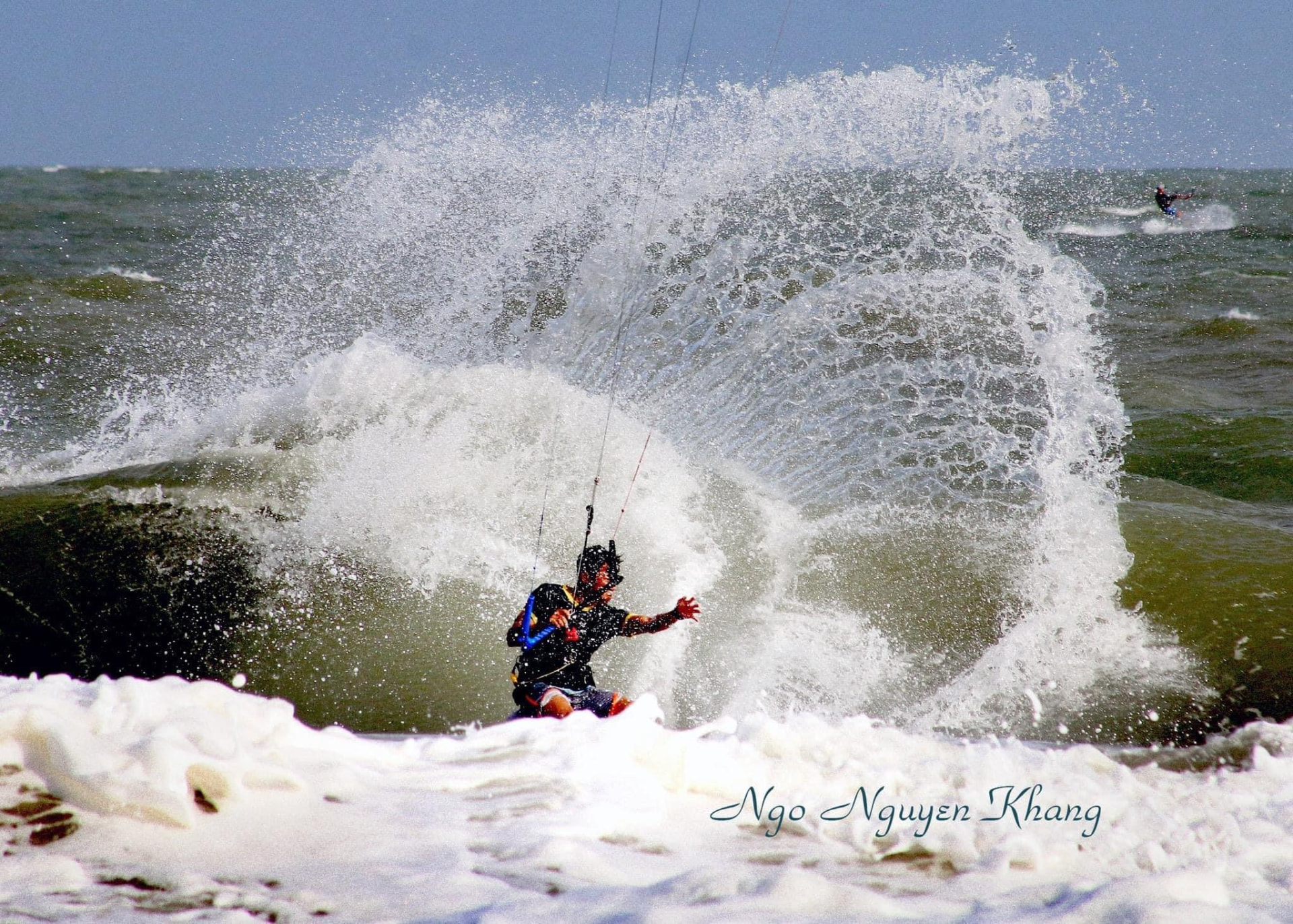 Kitesurfer blasting through spray on a windy day in Mui Ne